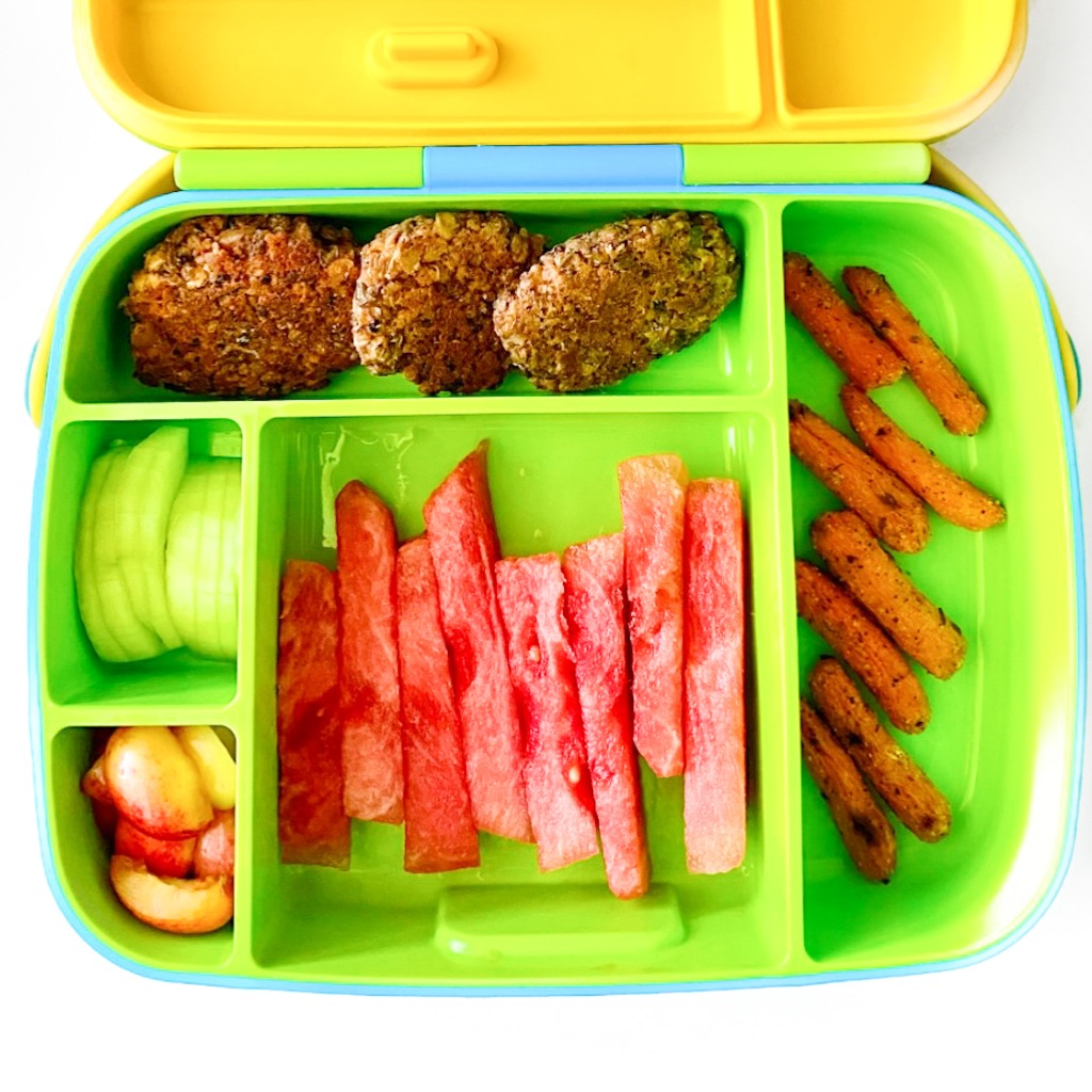 baby lunchbox with iron rich lentil patties, watermelon, cucumber slices, cherries, and roasted carrots